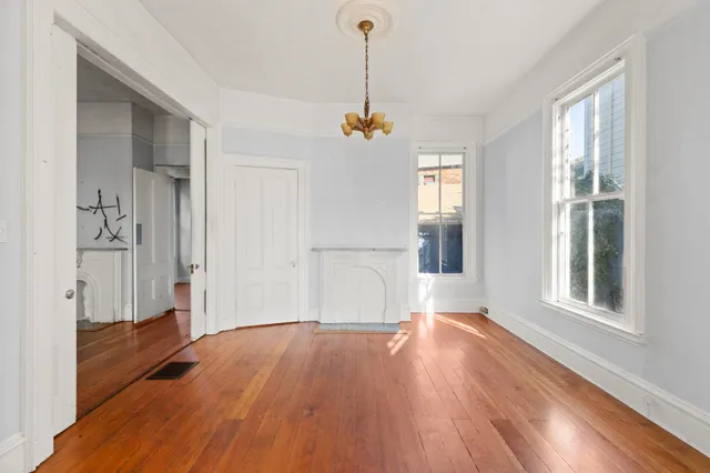 a view of empty room with wooden floor and fan