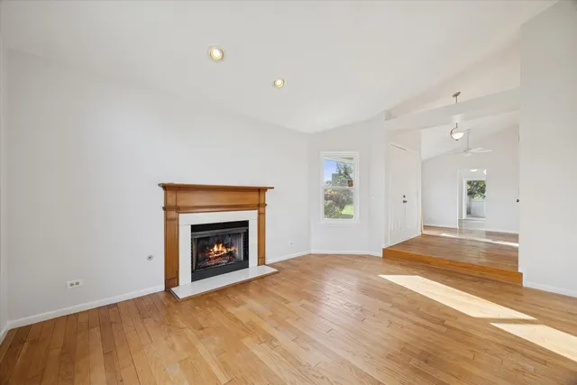 a view of an empty room with wooden floor fireplace and a window