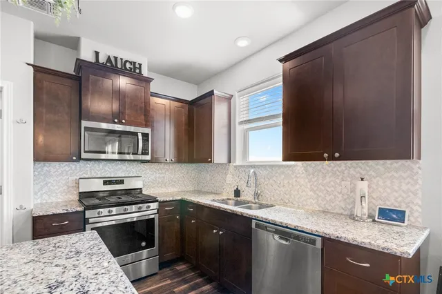 a kitchen with stainless steel appliances granite countertop a sink stove and microwave