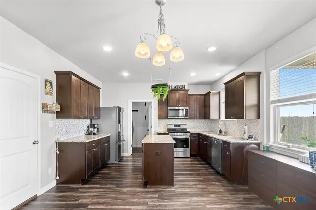 a large kitchen with a large counter top a sink cabinets and stainless steel appliances