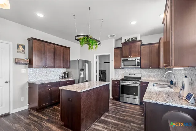 a kitchen with kitchen island granite countertop a sink stainless steel appliances and counter space