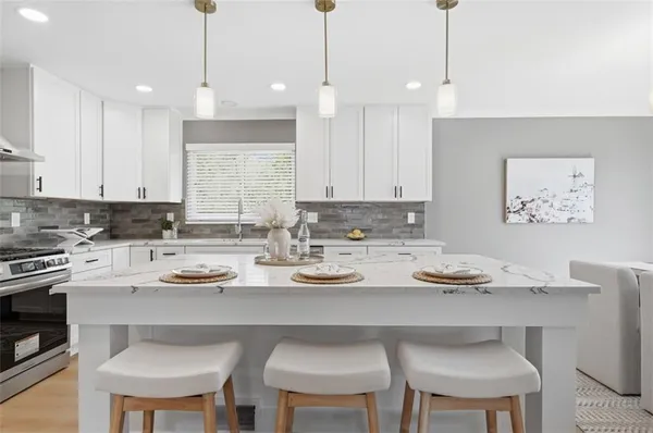 a kitchen with a dining table chairs and white cabinets