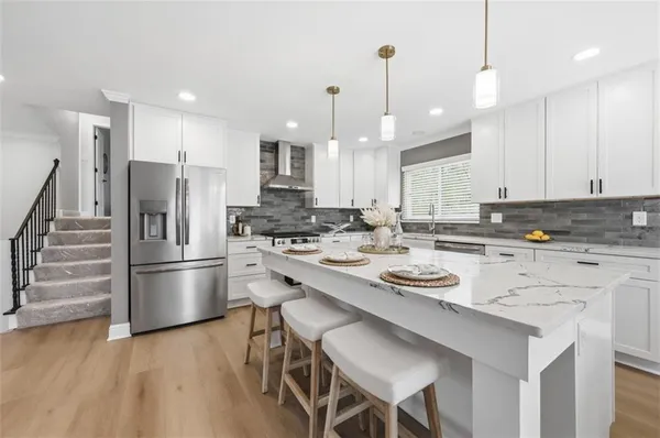a kitchen with stainless steel appliances a stove a sink a refrigerator and white cabinets with wooden floor