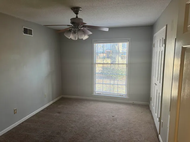 en empty room with windows and chandelier fan