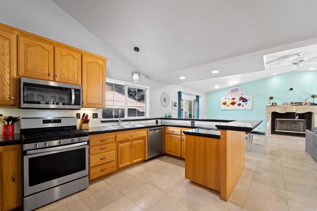 2461 Trace Road Spring Valley, CA 91978 - Photo 4 of 26 a large kitchen with stainless steel appliances granite countertop a stove top oven a sink dishwasher a dining table and chairs with wooden floor