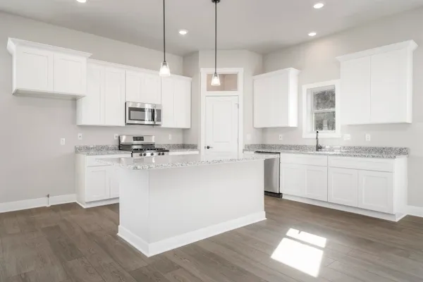 a kitchen with kitchen island granite countertop a sink cabinets and wooden floor