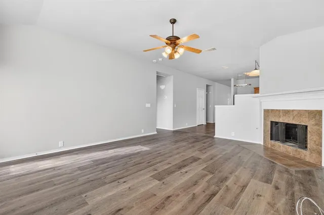 a view of an empty room with wooden floor and a fireplace