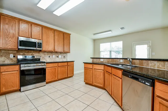 a large kitchen with stainless steel appliances granite countertop a stove sink microwave and cabinets