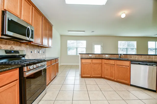 a kitchen with stainless steel appliances granite countertop a stove a sink and a microwave