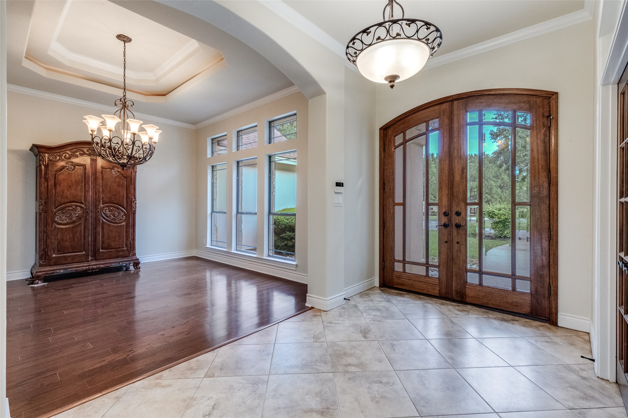 101 Copper Leaf Court Georgetown, TX 78633 - Photo 4 of 31 Entryway featuring double arched wood doors with glass panels, light-colored tile flooring, and a decorative semi-flush mount light fixture