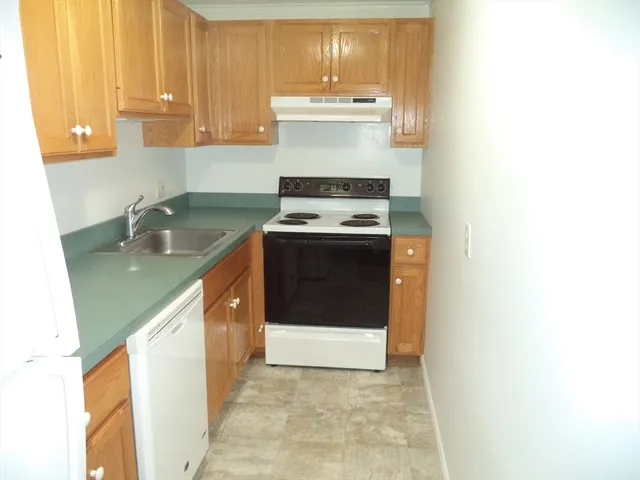 a utility room with stainless steel appliances granite countertop a stove a sink and a microwave