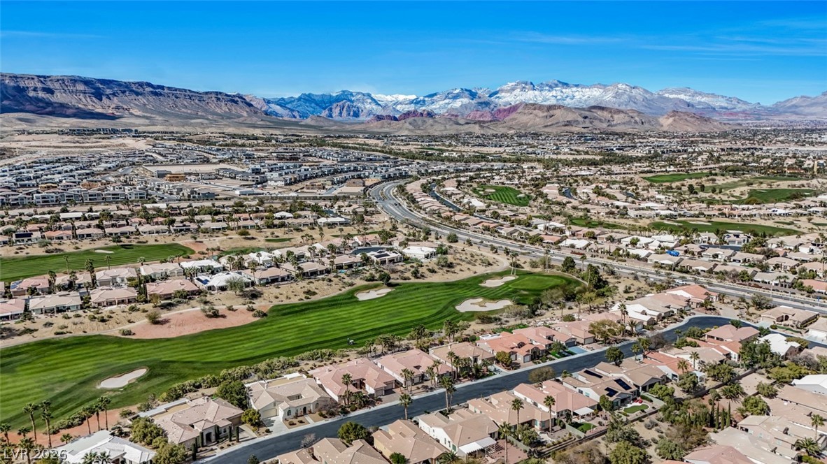 5015 Rivedro Street Las Vegas, NV 89135 - Photo 83 of 91 An aerial perspective reveals a vast community nestled beside a golf course, framed by distant snow-capped mountains.
