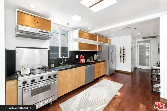 a kitchen with stainless steel appliances kitchen island granite countertop a stove a sink and a refrigerator
