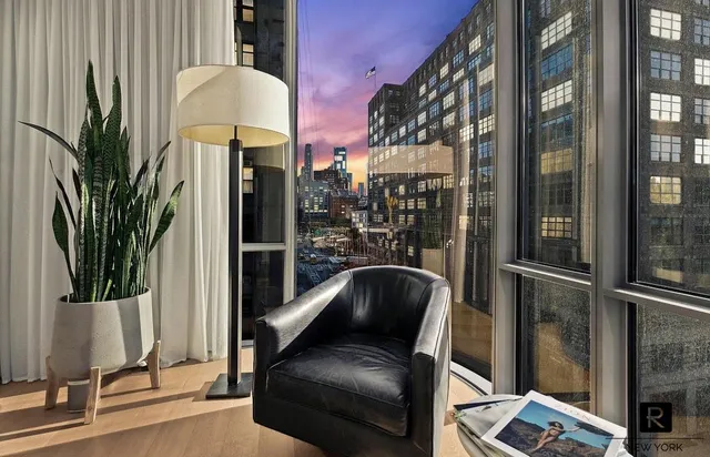 a living room with furniture a floor to ceiling window and potted plant