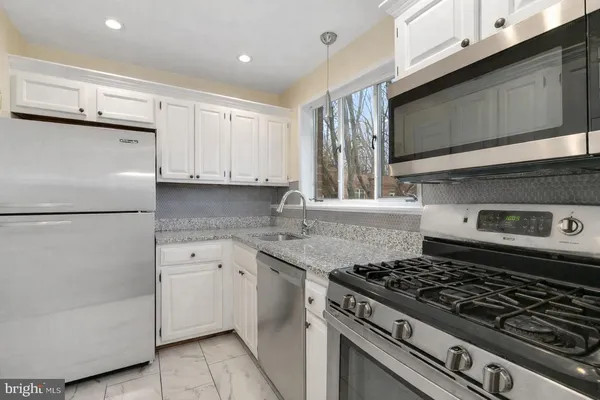 a kitchen with granite countertop a sink stove and refrigerator