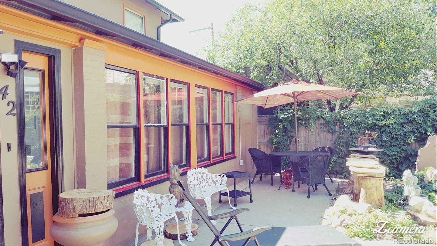 44 Lincoln Street Denver, CO 80203 - Photo 17 of 35 a view of a patio with a dining table and chairs under an umbrella with a small yard