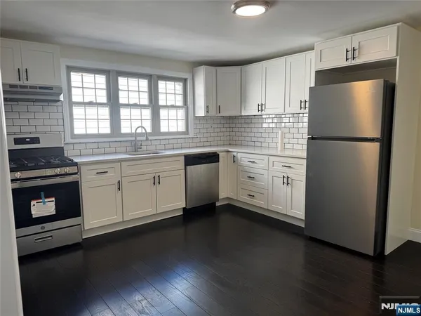 a kitchen with a refrigerator stove and wooden floor