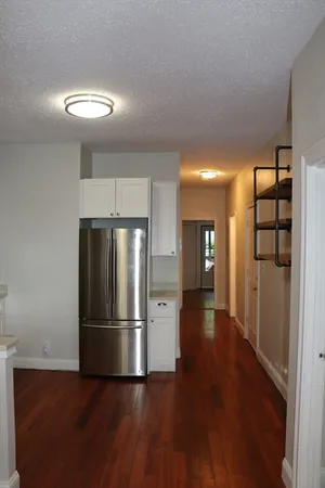 a view of a kitchen with a refrigerator and wooden floor