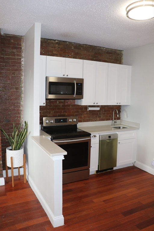 320 Warren Street, Unit 2 Boston, MA 02119 - Photo 3 of 22 a kitchen with granite countertop a sink and a stove top oven