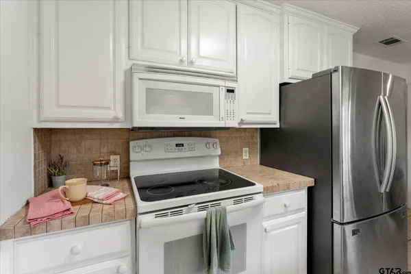 a kitchen with stainless steel appliances white cabinets and a refrigerator