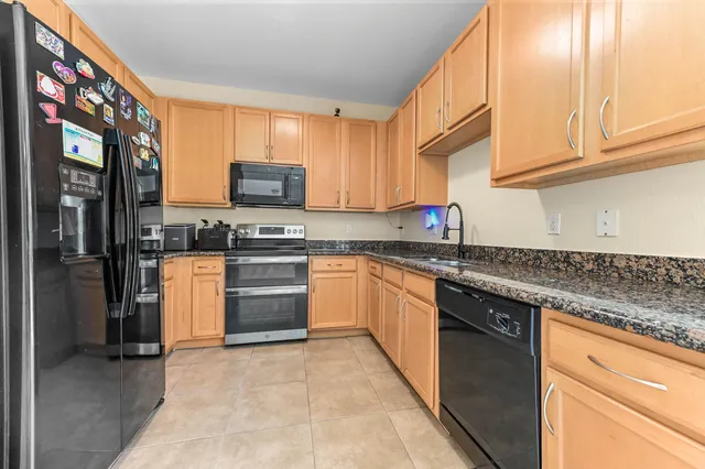 a kitchen with granite countertop a stove top oven microwave and cabinets
