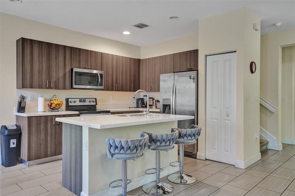 4875 Northwest 55th Place Tamarac, FL 33319 - Photo 18 of 44 a kitchen with a refrigerator a stove a sink and chairs