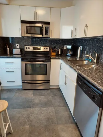 a kitchen with stainless steel appliances granite countertop a stove a sink and a microwave