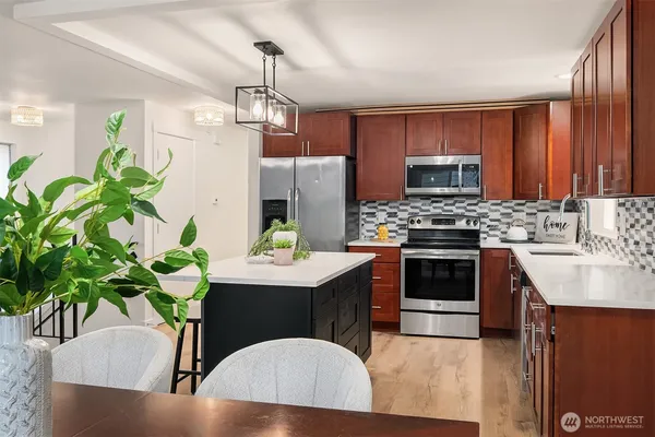 a kitchen with stainless steel appliances a kitchen island hardwood floor sink stove dining table and chairs