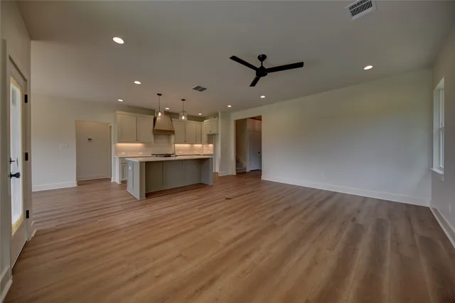 a view of kitchen and empty room with wooden floor and windows