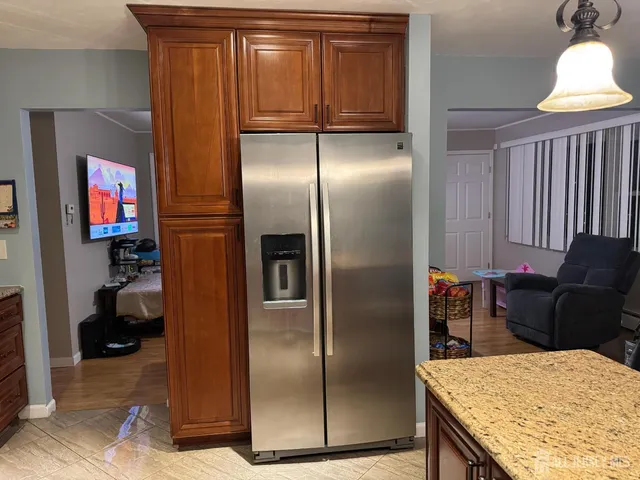 a kitchen with stainless steel appliances kitchen island granite countertop a refrigerator a stove and a sink with wooden floor