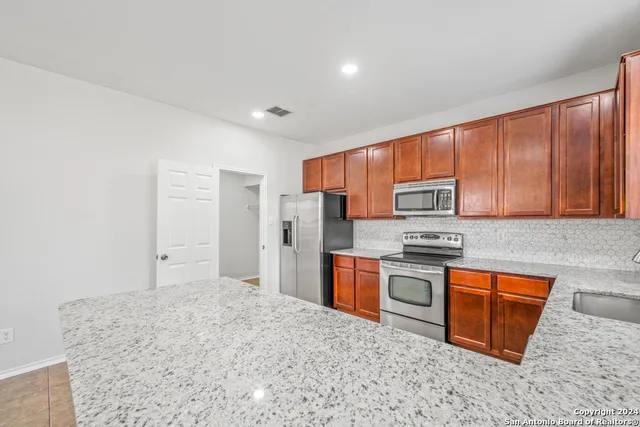 a kitchen with stainless steel appliances granite countertop a stove a sink dishwasher a refrigerator and cabinets with wooden floor