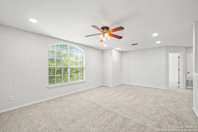 an empty room with a window and a chandelier fan