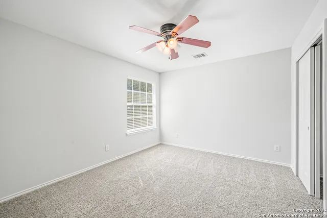 an empty room with a window and a ceiling fan