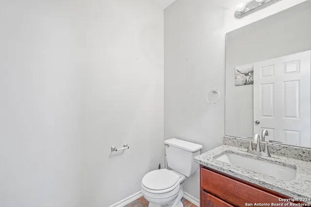 a bathroom with a granite countertop sink toilet and a mirror