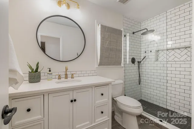 a bathroom with a granite countertop toilet sink and mirror