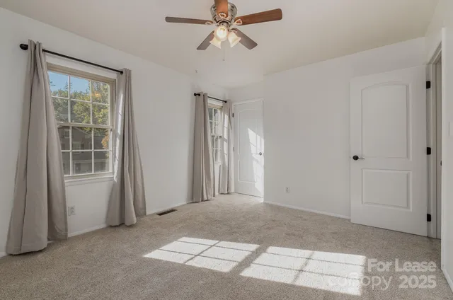 a view of empty room with windows and ceiling fan