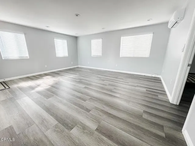 a view of an empty room with wooden floor and window