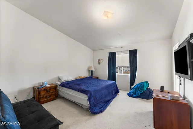 a living room with a bed and a flat screen tv