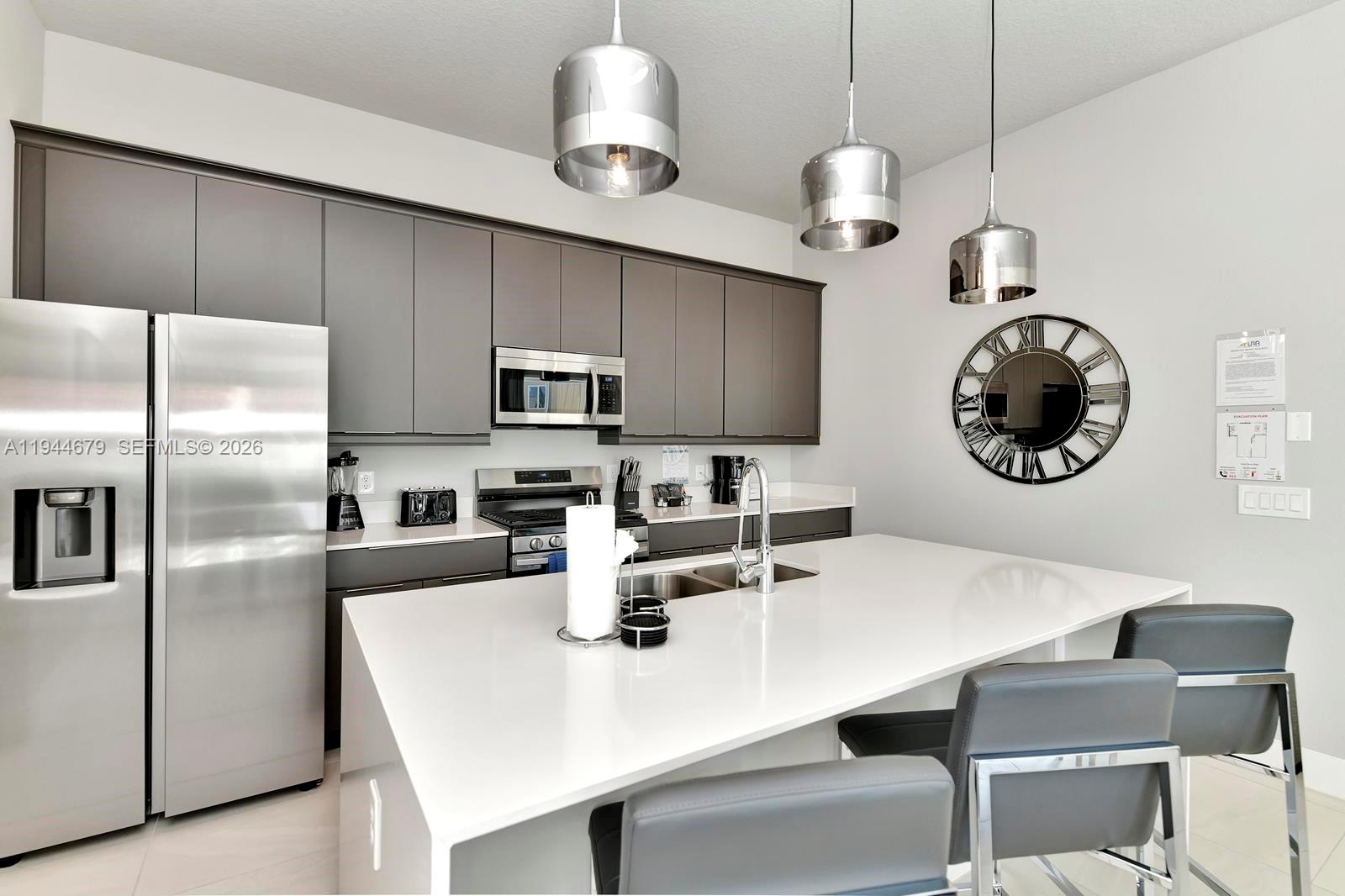 7740 Sandy Ridge Drive, Unit 136 Kissimmee, FL 34747 - Photo 4 of 26 a kitchen with stainless steel appliances a table chairs and a refrigerator