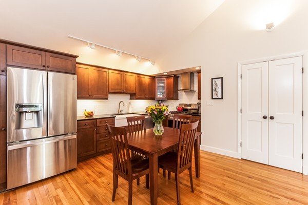 18 Mountain Road Waltham, MA 02451 - Photo 7 of 22 a kitchen with stainless steel appliances a refrigerator a stove a sink and a dining table with wooden floor