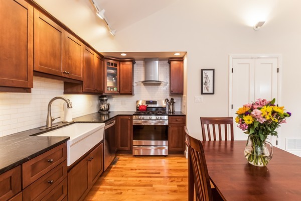18 Mountain Road Waltham, MA 02451 - Photo 8 of 22 a kitchen with stainless steel appliances granite countertop a refrigerator a sink dishwasher a stove top oven a dining table and chairs with wooden floor