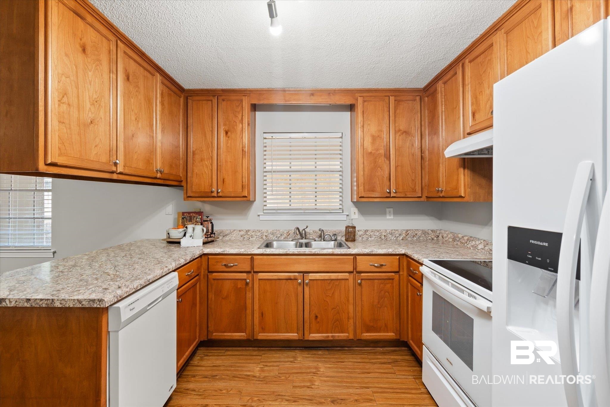 6848 Sandra Drive Theodore, AL 36582 - Photo 17 of 21 Kitchen featuring sink, a textured ceiling, light wood-type flooring, kitchen peninsula, and white appliances
