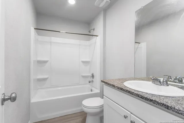 a bathroom with a granite countertop sink a toilet and a bathtub