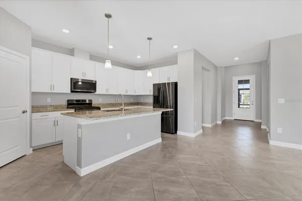 a kitchen with a stove a sink a center island and a wooden floor
