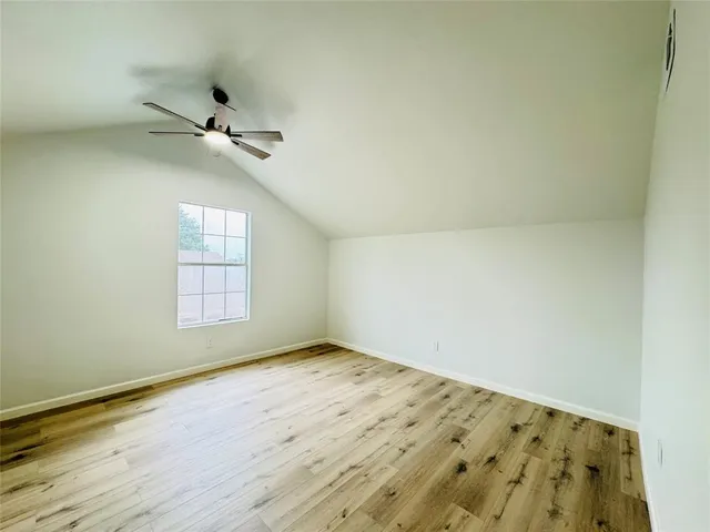 an empty room with wooden floor and fan