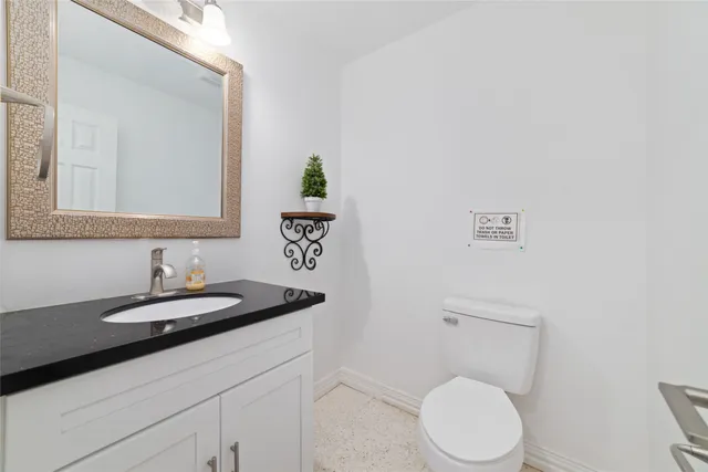 a bathroom with a granite countertop toilet sink and mirror