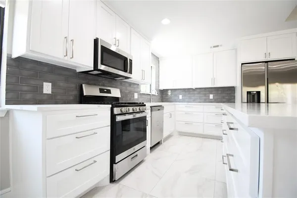 a kitchen with granite countertop white cabinets and stainless steel appliances
