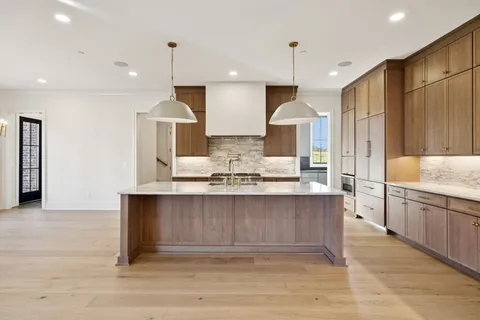 a view of an empty room with wooden floor and staircase