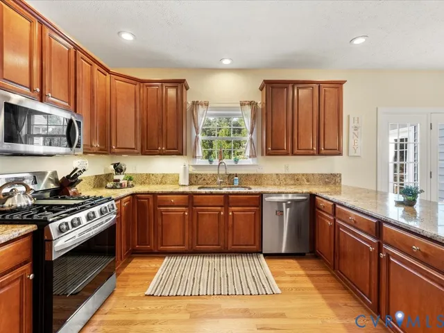 a kitchen with stainless steel appliances granite countertop wooden cabinets stove top oven and granite counter top
