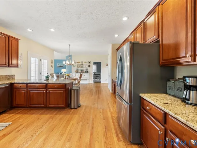 a kitchen with stainless steel appliances granite countertop a refrigerator a sink dishwasher a stove and a wooden cabinets